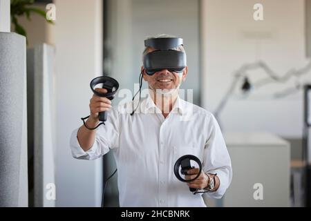 Smiling businessman wearing virtual reality simulator in office Stock Photo