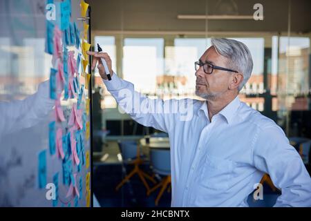 Businessman planning strategy on sticky notes in office Stock Photo