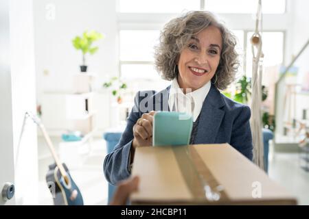 Senior real estate agent with folder looking up while standing in living room at apartment Stock Photo