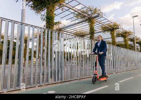 Businessman riding electric push scooter on road Stock Photo