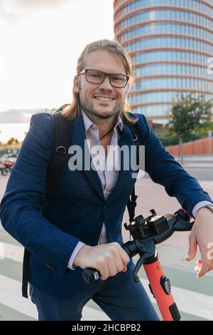 Businessman standing with electric scooter on road Stock Photo