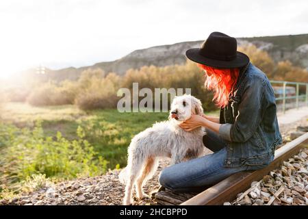 Woman stroking Border Collie dog sitting on railroad track Stock Photo