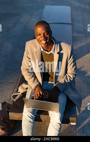 Smiling businessman sitting on bench Stock Photo