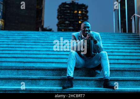 Businessman sitting on steps in subway at night Stock Photo