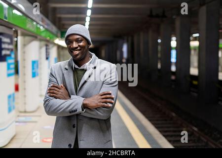 Smiling businessman standing in front of train at railroad station Stock Photo