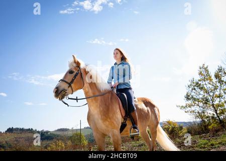 Woman horseback riding in front of sky on sunny day Woman horseback riding in front of sky on sunny day