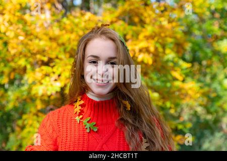 Smiling young woman with autumn leaves in forest Stock Photo