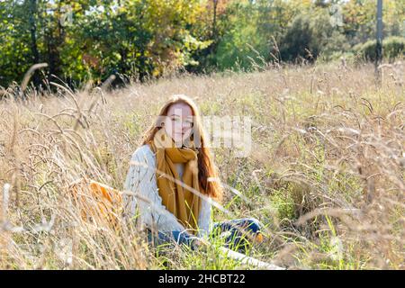 Young woman sitting amidst grass on sunny day Stock Photo