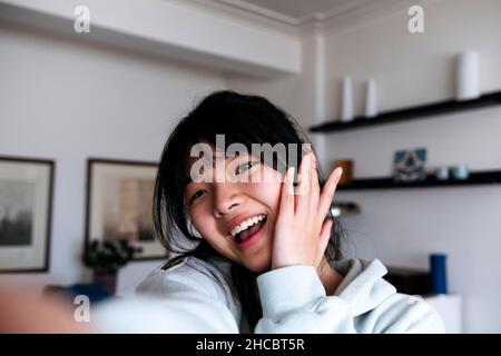 Cheerful young woman taking selfie at home Stock Photo