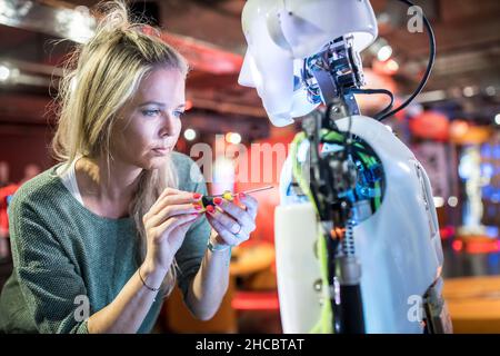 Serious tech developer working with screwdriver on human robot at workshop Stock Photo