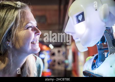 Happy technician looking at human robot with heart shape in eye Stock Photo