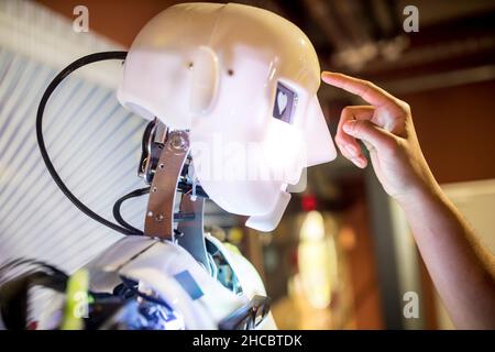 Developer touching human robot on head at workshop Stock Photo