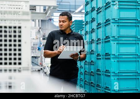 Inspector with tablet PC looking at crates in warehouse Stock Photo