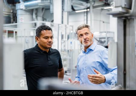 Businessman explaining engineer and looking at machine in industry Stock Photo