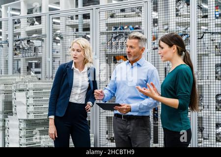 Businessman having discussion with coworkers in factory Stock Photo
