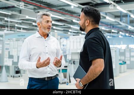 Businessman having discussion with engineer at factory Stock Photo