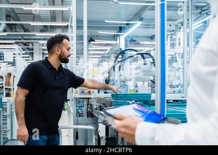 Businessman explaining maintenance engineer over factory production line Stock Photo