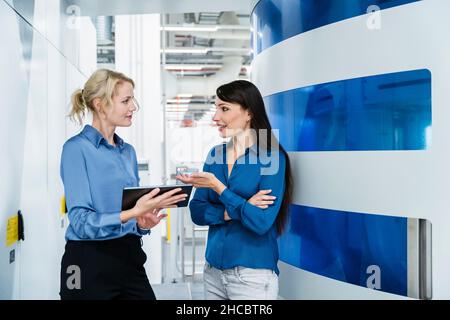 Businesswomen discussing over tablet PC at factory Stock Photo