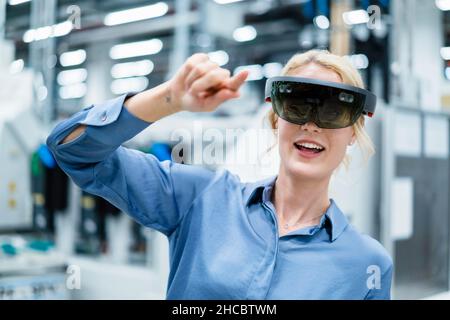 Businesswoman using augmented reality glasses at industry Stock Photo