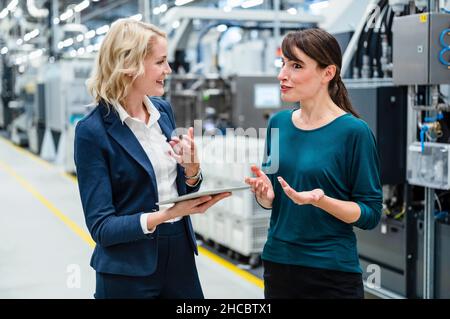 Businesswoman having discussion with colleague at industry Stock Photo