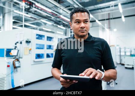 Maintenance engineer holding tablet PC at factory Stock Photo