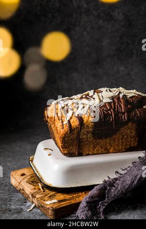 Sliced banana cake with walnuts and chocolate sauce stacked on cooling rack Stock Photo