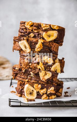 Sliced banana cake with walnuts and chocolate sauce on cutting board Stock Photo