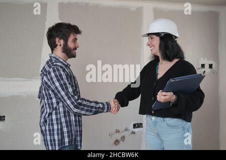 Man and female architect shaking hands after contract signature of buying house. Stock Photo
