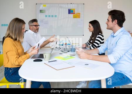 Smiling colleague looking at businessman in coworking office Stock Photo