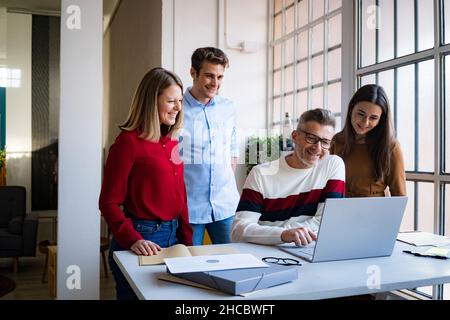 Businessman using laptop amidst colleagues in office Stock Photo