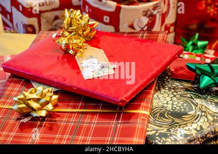Piles of Christmas presents, carefully wrapped in festive paper and decorated with bows and ribbons. Stock Photo