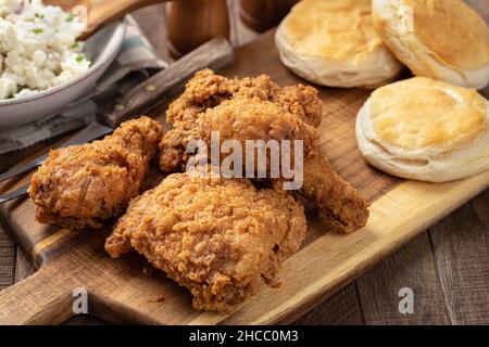 Cispy fried chicken leg and thigh dinner  with biscuits and mashed potatoes on a rustic wooden table Stock Photo