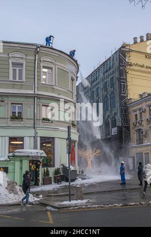 Moscow, Russia - 20 December 2021 , Utility workers clear snow from the roof of a building on Kuznetsky Most Street Stock Photo
