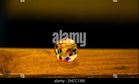 A fiber made dice in a wooden surface and six on top Stock Photo