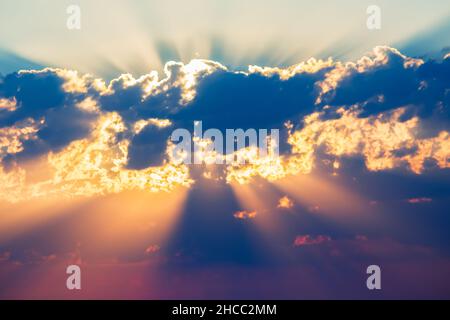 bright colored sunbeams behind the clouds Stock Photo