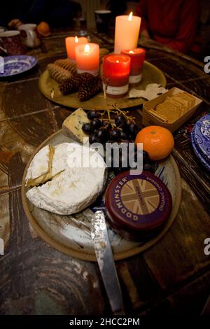 A selection of cheese on table with candles and open fire Stock Photo