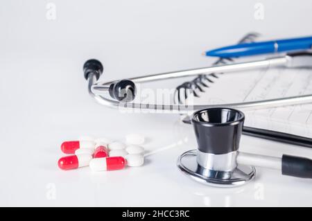 stethoscope, medical mask, notepad, blue pencil and pills on white background close up Stock Photo