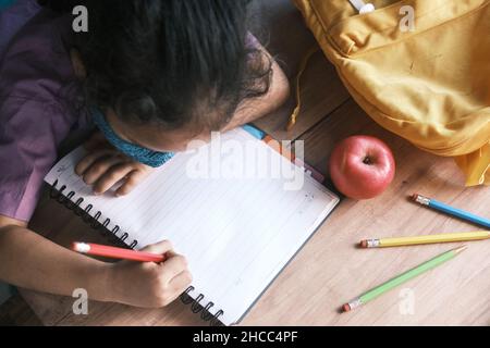 child girl in face mask hand drawing on notepad. Stock Photo