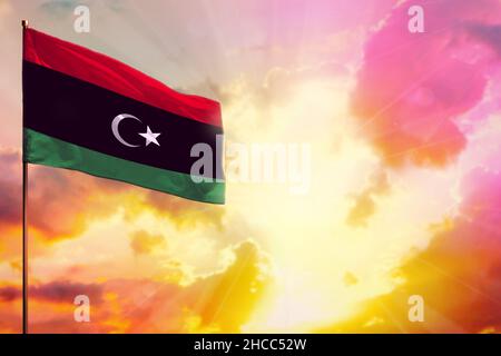 Fluttering Libya flag in left top corner mockup with the place for your information on beautiful colorful sunset or sunrise background. Stock Photo