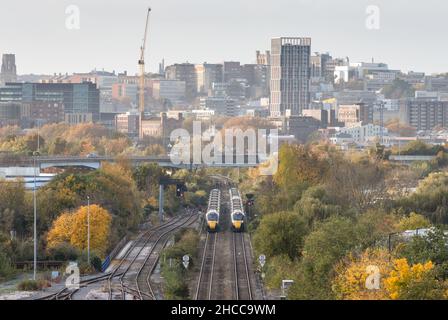 Great Western Railway intercity express passenger trains pass on the approach to Bristol Temple Meads station, with Bristol city centre behind. Stock Photo