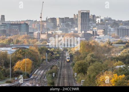 Great Western Railway intercity express passenger trains pass on the approach to Bristol Temple Meads station, with Bristol city centre behind. Stock Photo