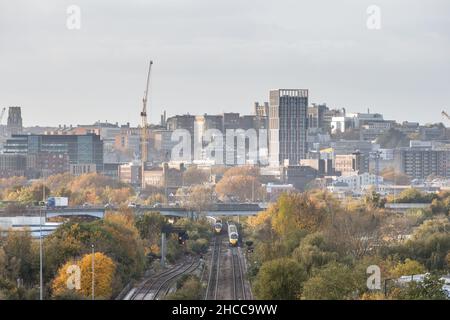 Great Western Railway intercity express passenger trains pass on the approach to Bristol Temple Meads station, with Bristol city centre behind. Stock Photo