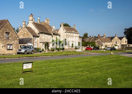 Traditional stone cottages and houses are arranged around Biddestone village green in England's Cotswold Hills. Stock Photo