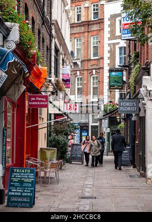 Pedestrians walk past shops and cafes at Red Lion Square in central London. Stock Photo