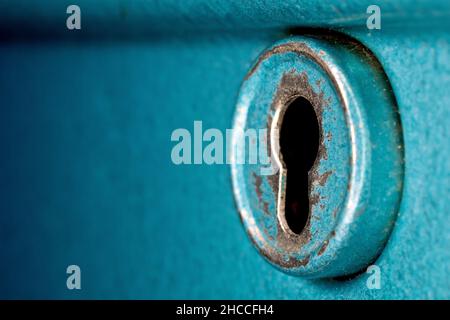 Close up still life of the round keyhole on an old blue metal cashbox. Stock Photo