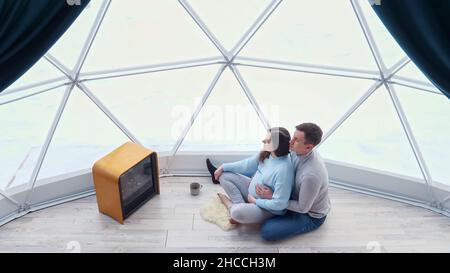 Man strokes pregnant woman belly sitting near fireplace Stock Photo
