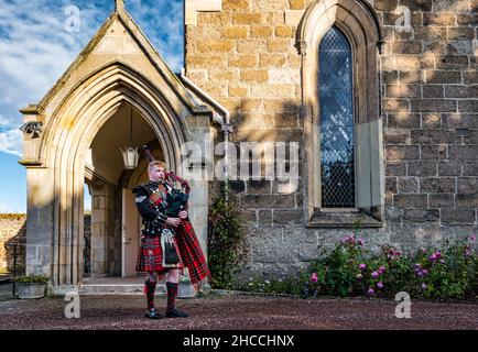 A piper from Scots Guards plays bagpipes outside Holy Trinity Church, Haddington, East Lothian, Scotland, UK Stock Photo