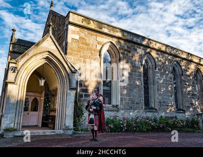 A piper from Scots Guards plays bagpipes outside Holy Trinity Church, Haddington, East Lothian, Scotland, UK Stock Photo