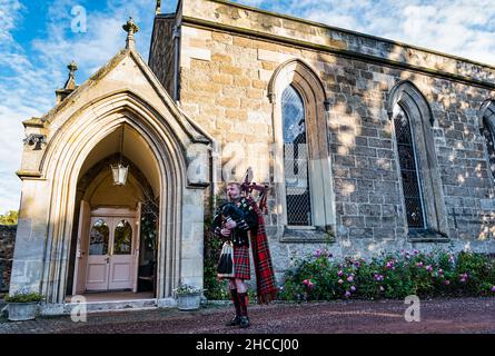 A piper from Scots Guards plays bagpipes outside Holy Trinity Church, Haddington, East Lothian, Scotland, UK Stock Photo