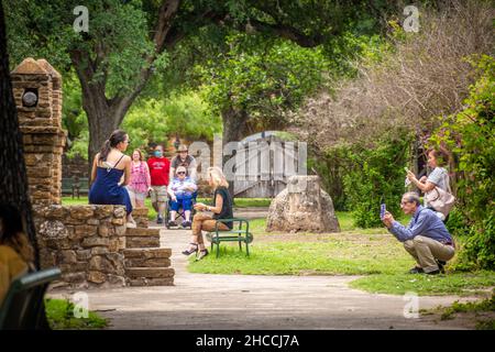 People gathered and taking photos at a stone brick fountain Stock Photo